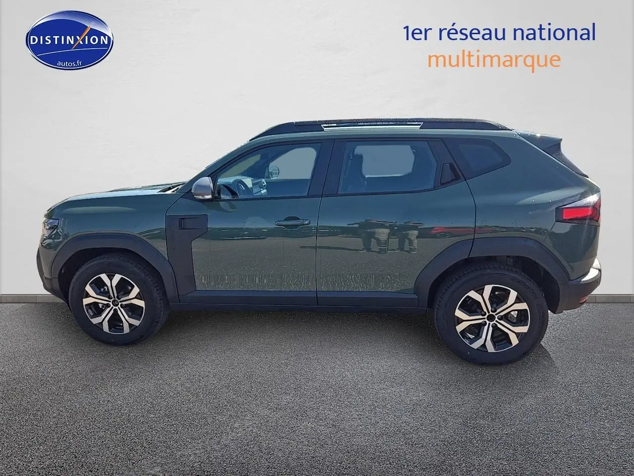 Profil latéral gauche du Dacia Duster 2025 vert kaki avec jantes alu et barres de toit visibles.