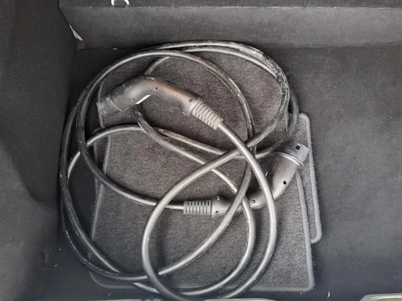 Câble de recharge électrique noir enroulé dans le coffre d'une Renault ZOE blanche Z.E. R240 Life 2016.