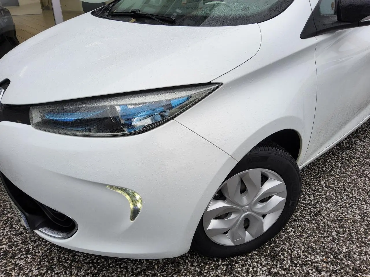 Vue 3/4 avant droit d'une Renault ZOE blanche avec phares à LED bleutés et enjoliveurs 15 pouces.