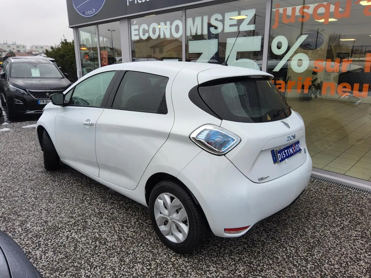Vue 3/4 arrière droite d'une Renault ZOE blanche avec vitres arrière surteintées et feux arrière au design distinctif.