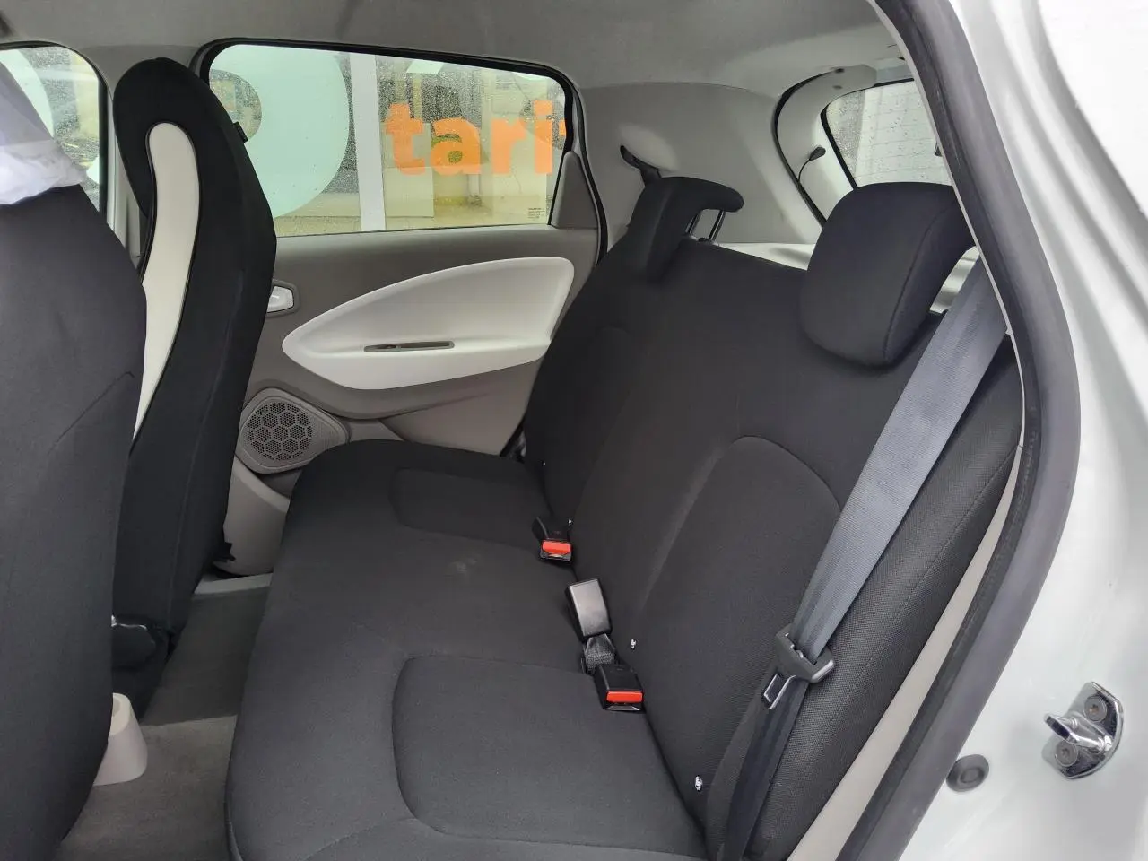 Vue intérieure côté droit sur la banquette arrière noire de la Renault ZOE blanche, avec appuie-têtes réglables.