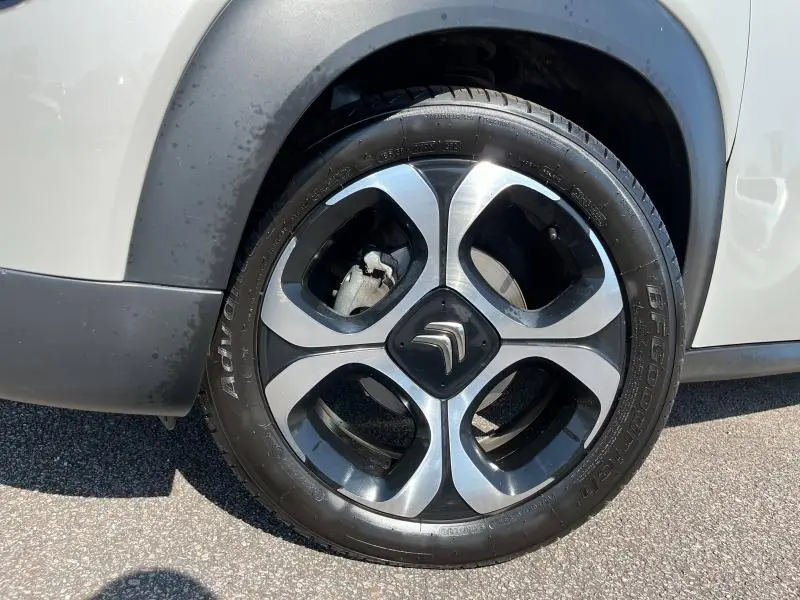 Gros plan sur la roue avant droite de la Citroën C3 Aircross sable avec jante diamantée noire et argentée.