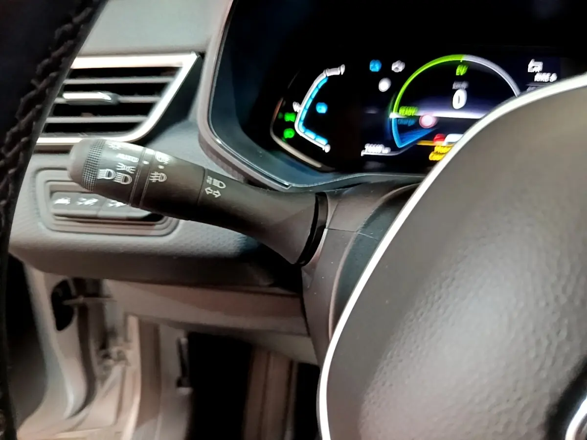 Gros plan sur la manette de commande des phares et clignotants à gauche du volant cuir d’une Renault Clio Business E-TECH 140 gris foncé.