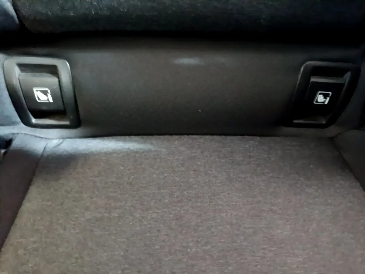 Détail des commandes de rabattement des sièges arrière sur la banquette d'une Renault Clio Business E-TECH 140 gris foncé.