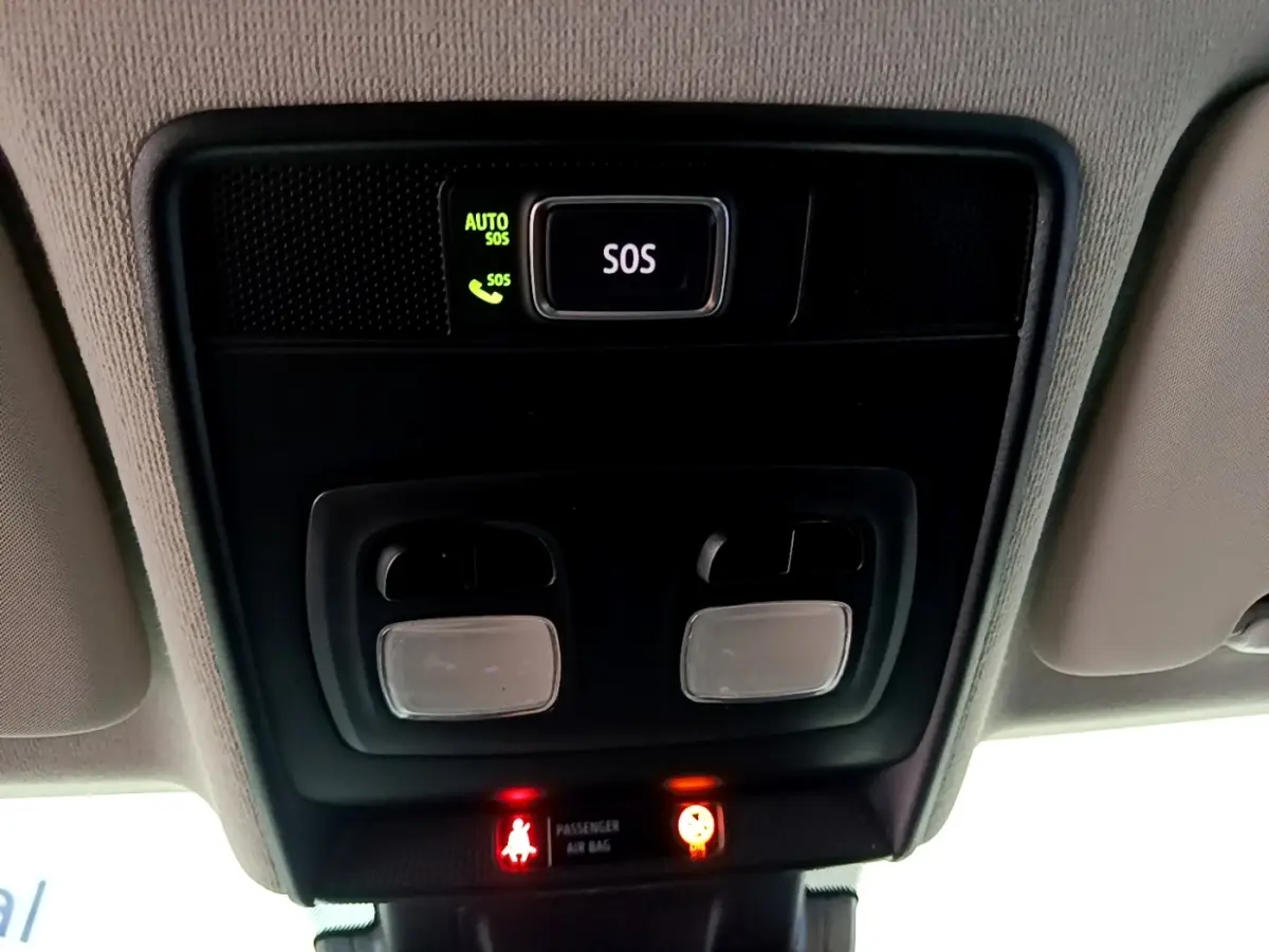 Vue rapprochée du plafonnier intérieur noir avec bouton SOS éclairé et voyants de sécurité rouges dans une Renault Clio gris foncé.