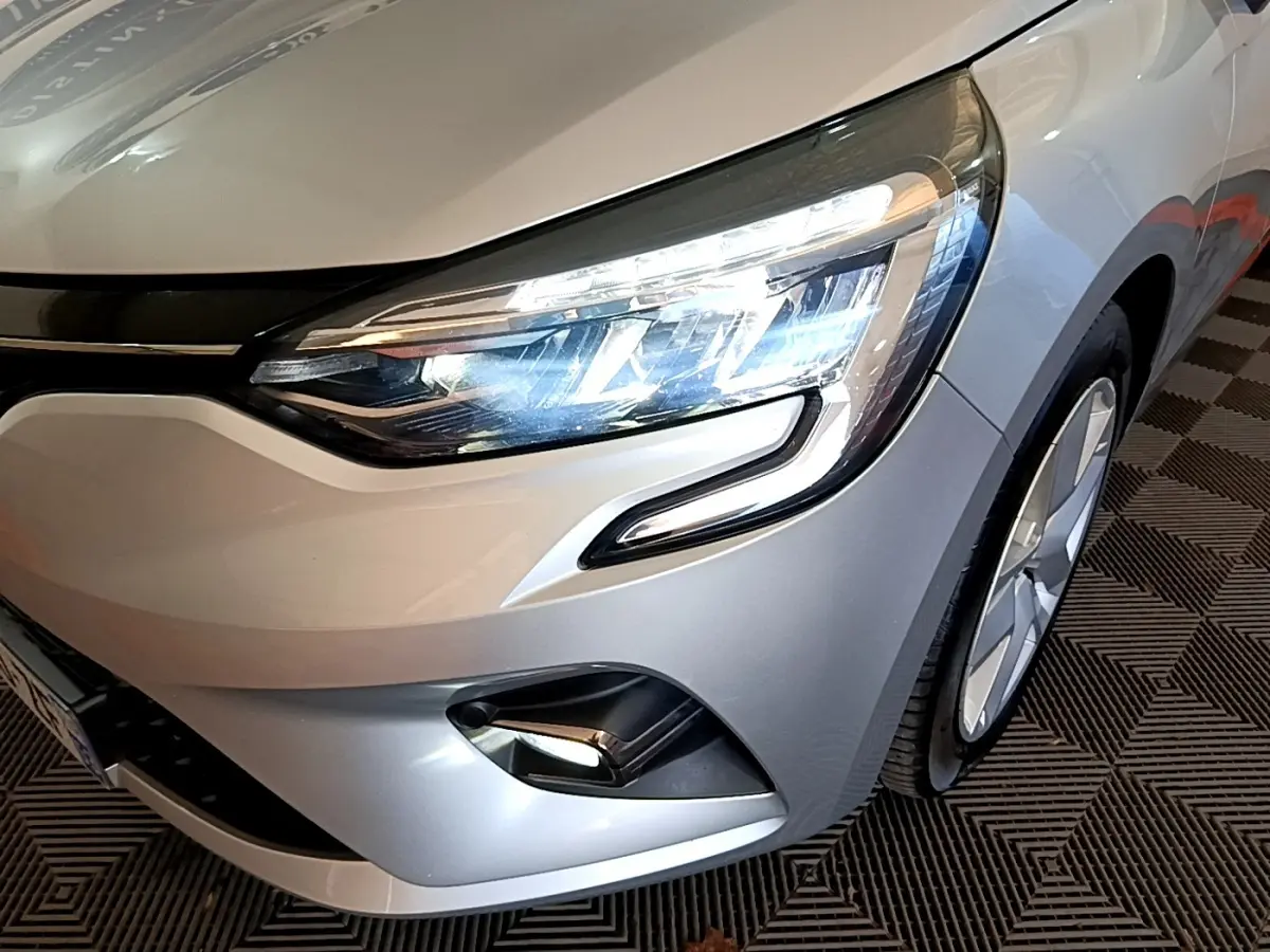 Gros plan sur l'avant droit gris foncé de la Renault Clio Business E-TECH 140 2022, avec phares LED allumés.