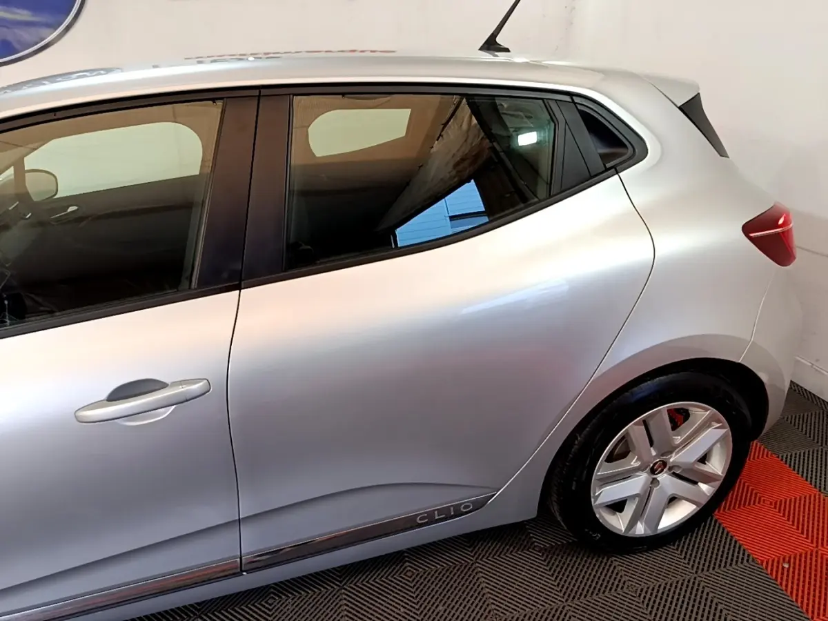 Vue latérale droite d'une Renault Clio gris clair avec jantes alliage et logo Clio sur la porte arrière.