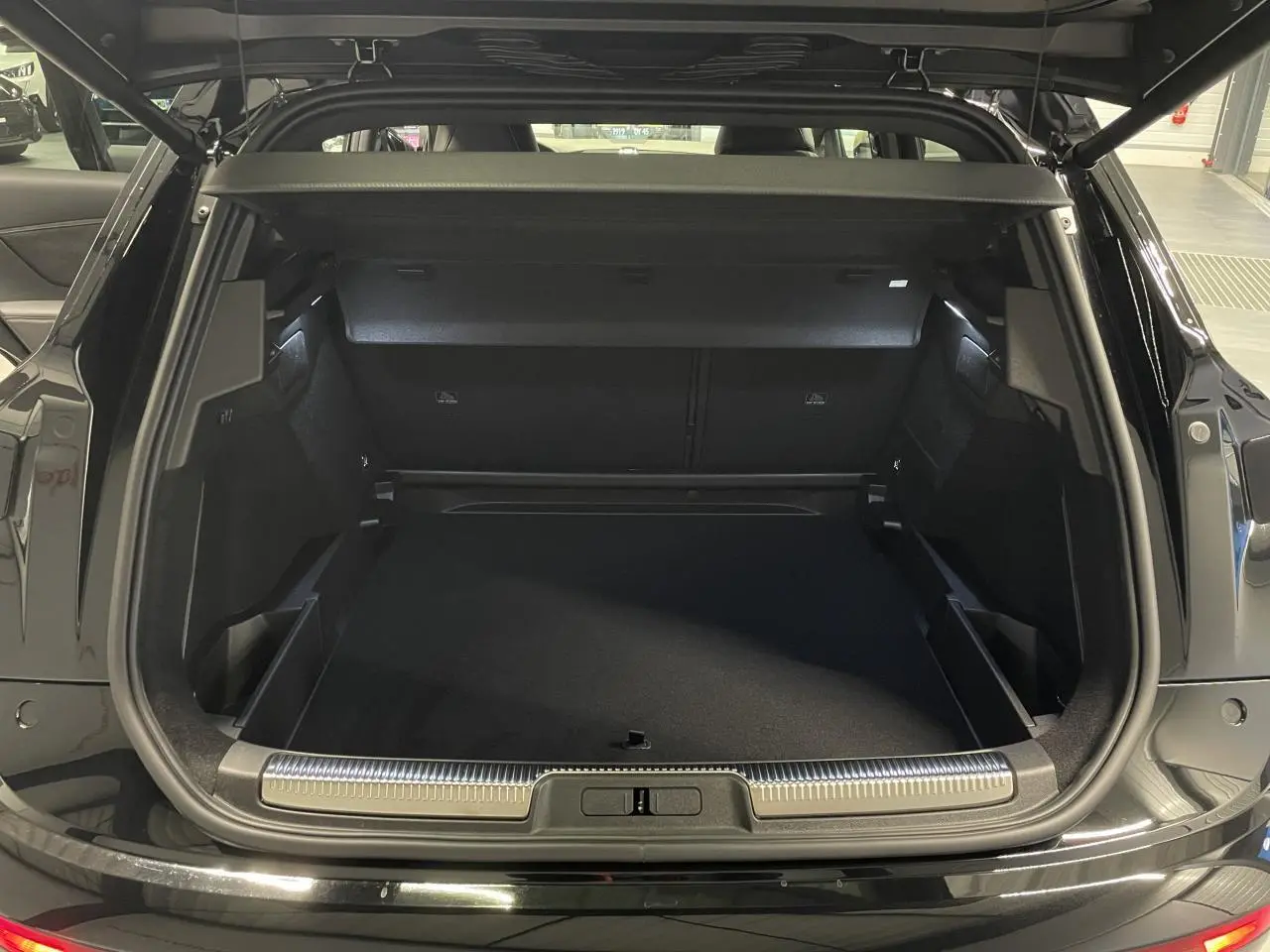 Coffre ouvert vu de l'arrière d'un DS7 Crossback noir métallisé avec seuil de coffre chromé et intérieur spacieux.