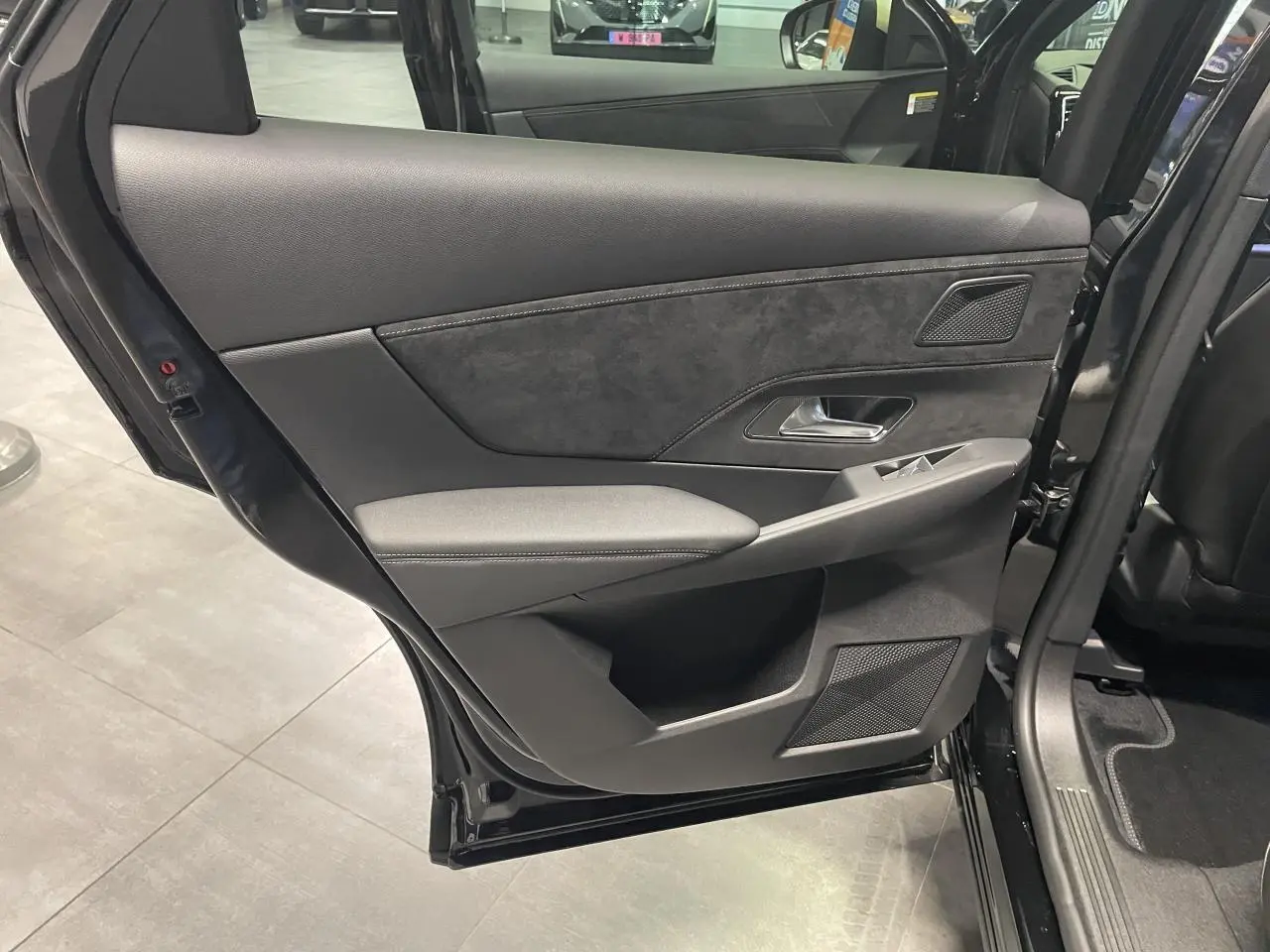 Vue intérieure côté gauche de la porte arrière du DS7 Crossback noir métallisé avec garniture Alcantara et commandes de vitres.