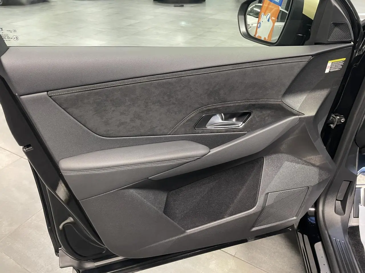 Vue intérieure côté gauche de la porte avant d’un DS7 Crossback noir métallisé avec garniture Alcantara et surpiqûres.