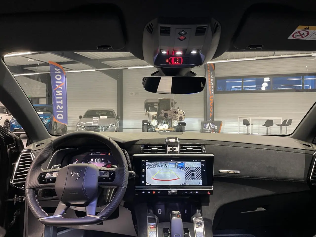 Vue intérieure avant du DS7 Crossback noir métallisé, volant cuir perforé et écran tactile affichant la caméra de recul.
