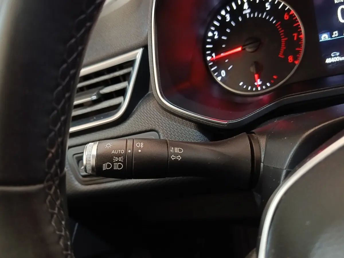 Gros plan sur la manette de commande des phares et clignotants côté gauche du tableau de bord de la Renault Clio Business blanche 2021.