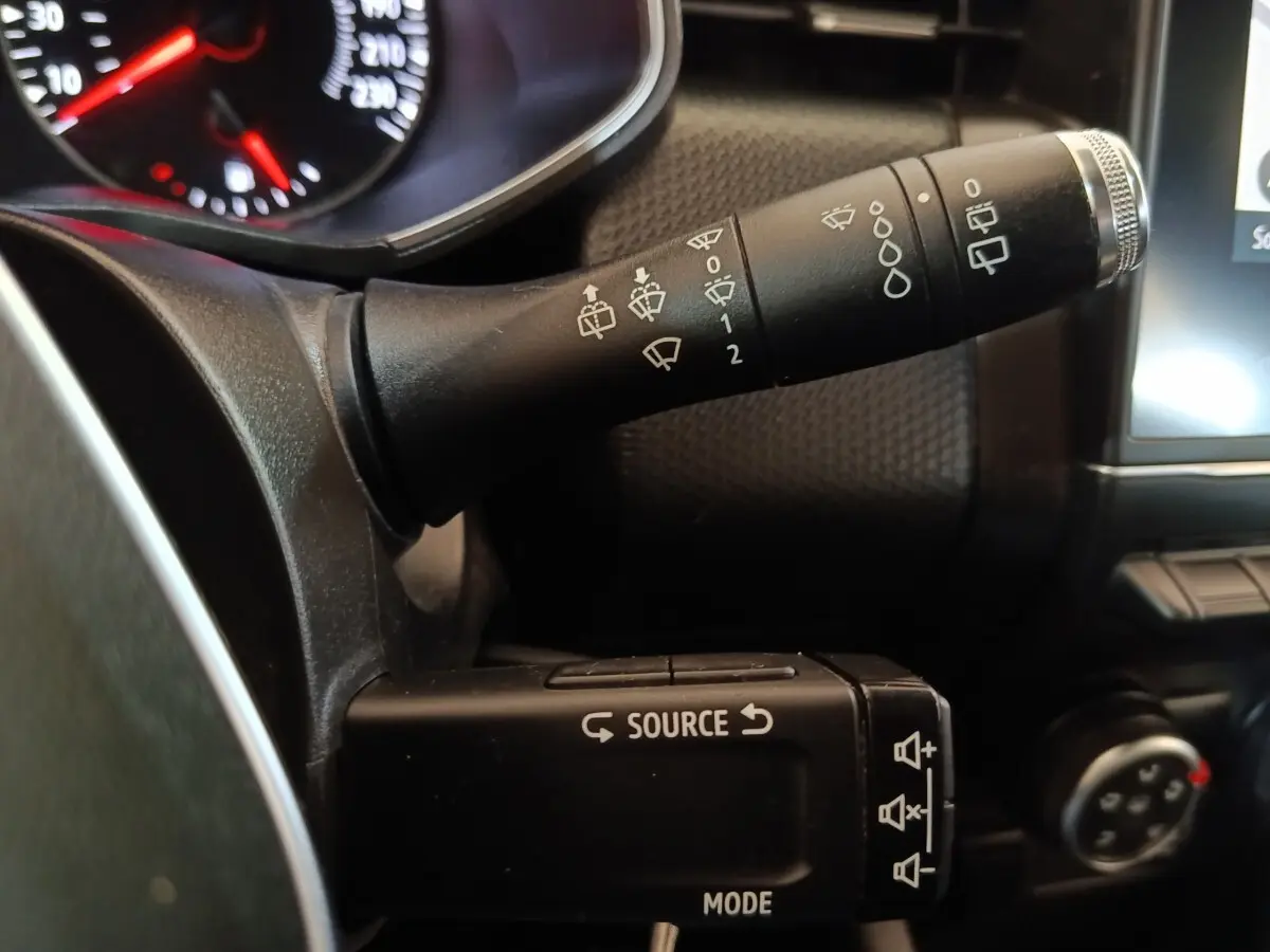 Gros plan sur les commandes au volant noir de la Renault Clio Business, avec tableau de bord partiellement visible.