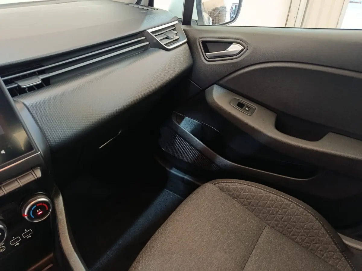 Intérieur côté passager de la Renault Clio Business blanc, tableau de bord texturé et siège tissu gris.