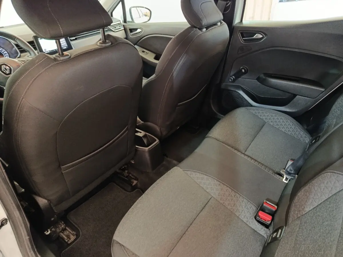 Vue intérieure arrière côté droit de la Renault Clio Business blanche, montrant la banquette tissu gris et les dossiers des sièges avant noirs.