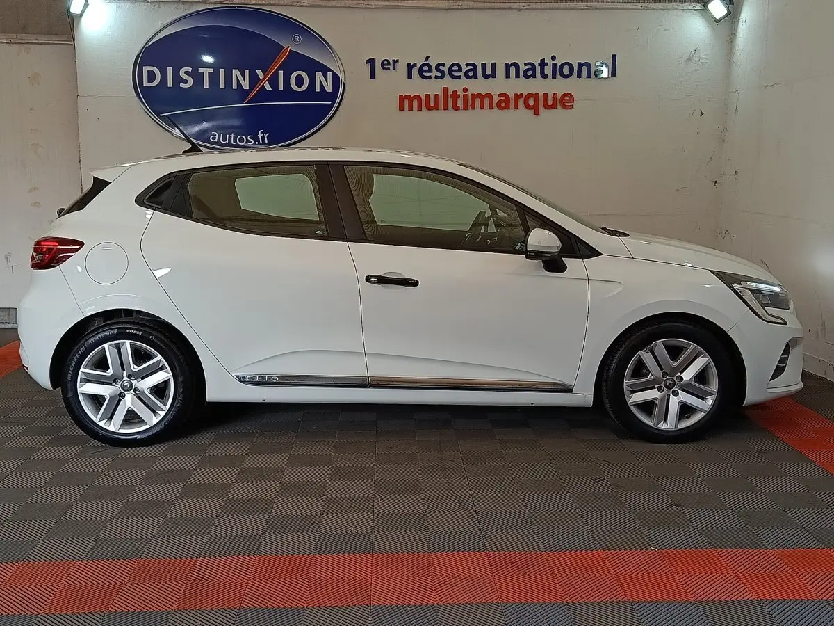 Profil côté gauche d'une Renault Clio Business blanche de 2021, avec jantes alliage et logo Clio sur la porte arrière.