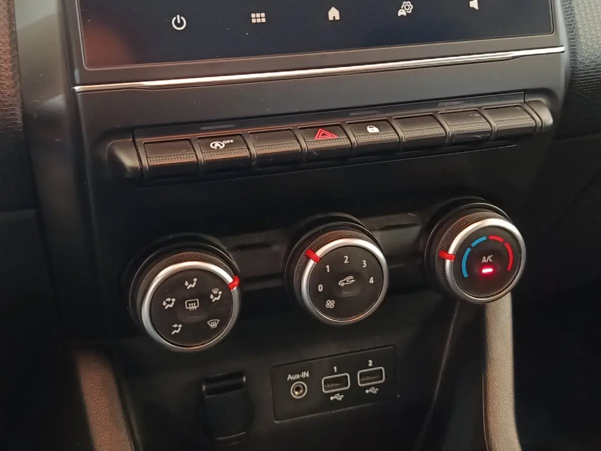 Gros plan sur la console centrale de la Renault Clio Business blanche, montrant les commandes de climatisation et les ports USB.