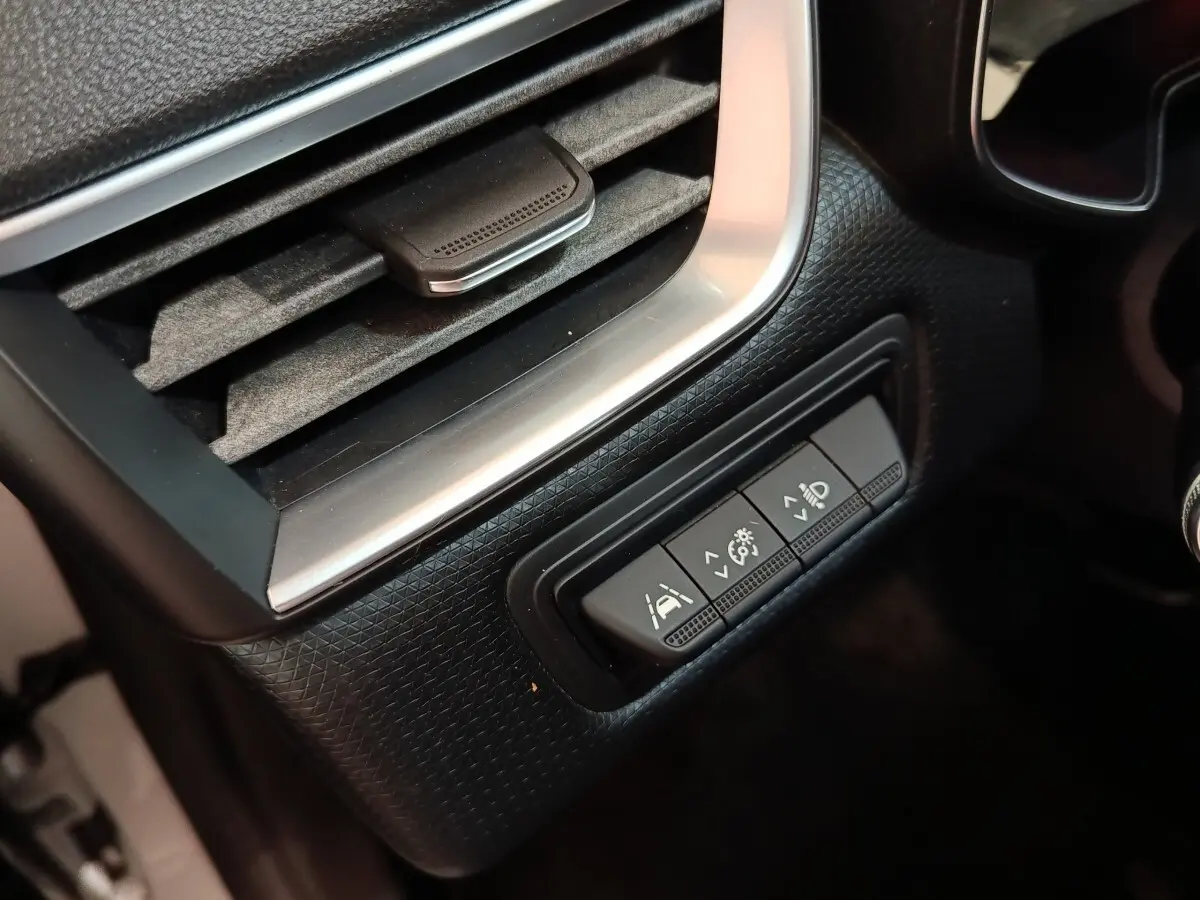 Détail intérieur du tableau de bord de la Renault Clio Business blanc, avec commandes d'assistance et réglage phares.