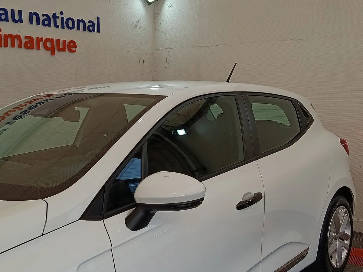 Profil côté gauche de la Renault Clio Business blanche 2021, avec rétroviseur et poignées noires contrastantes.