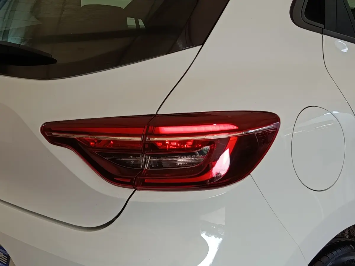 Gros plan sur le feu arrière droit d’une Renault Clio blanche de 2021, avec la trappe à carburant visible.