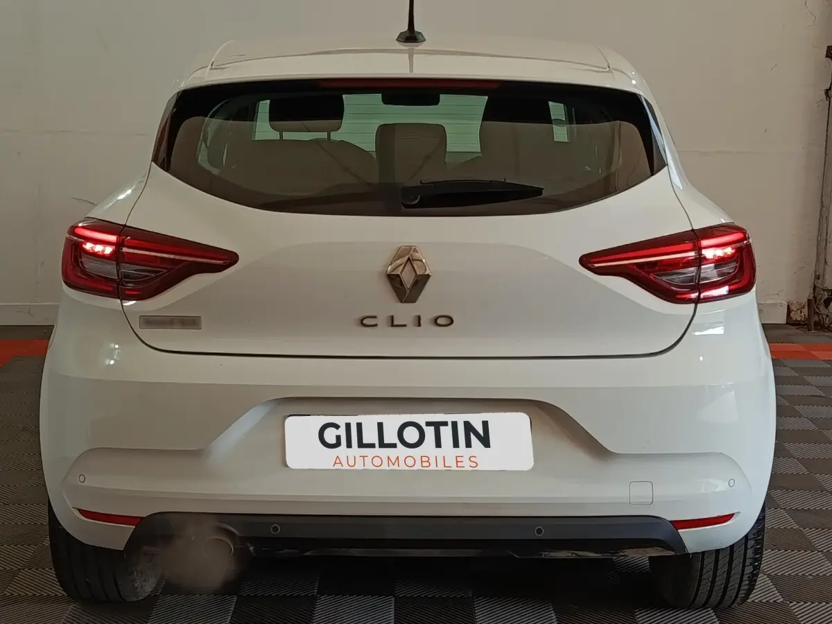 Vue arrière d'une Renault Clio Business blanche de 2021 avec feux LED allumés dans un garage.