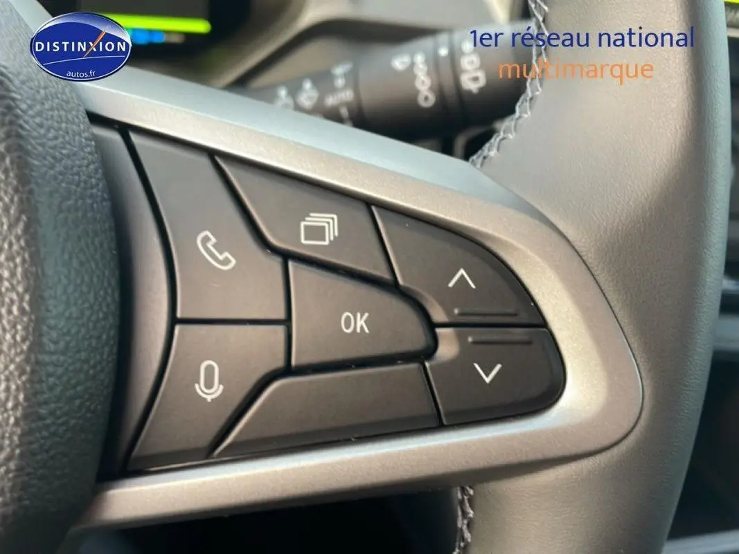 Gros plan sur les commandes multifonctions noires du volant gris du Dacia Bigster 2026, avec boutons appel et navigation.