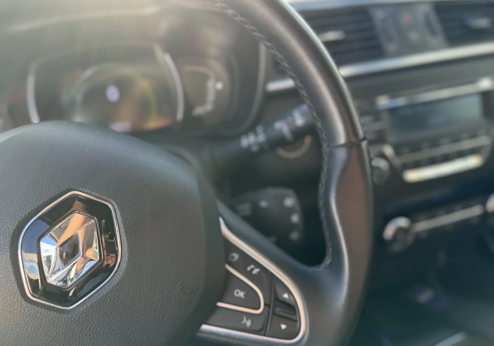 Gros plan sur le volant en cuir noir du Renault Kadjar 2019, avec commandes intégrées et tableau de bord flou en arrière-plan.