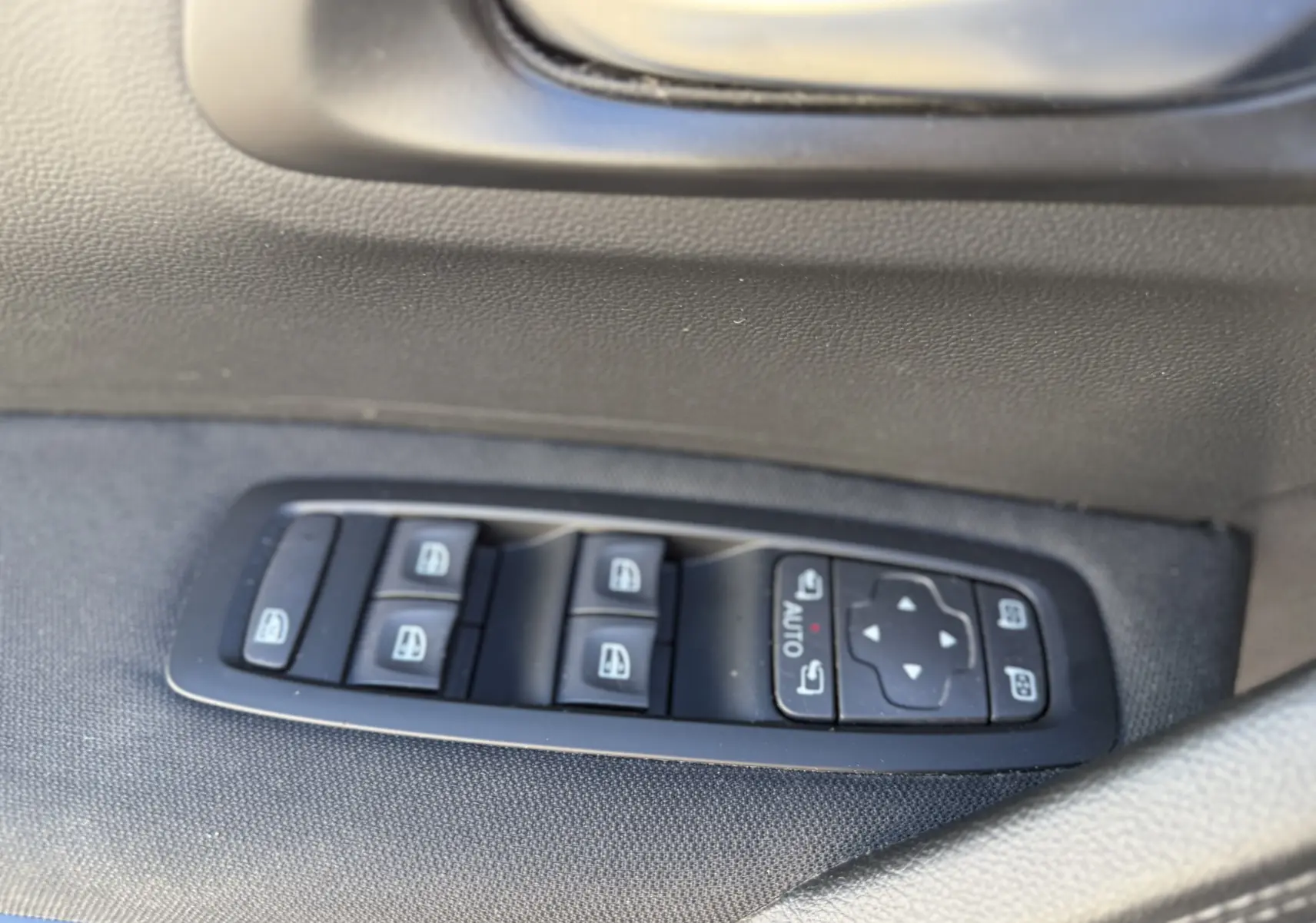 Gros plan sur les commandes des vitres électriques côté gauche du Renault Kadjar 2019, finition tissu noire.