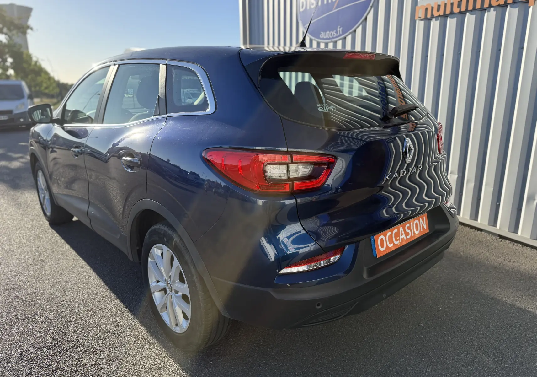 Renault Kadjar bleu vue 3/4 arrière droit, avec feux arrière LED et plaque occasion visible sur parking extérieur.