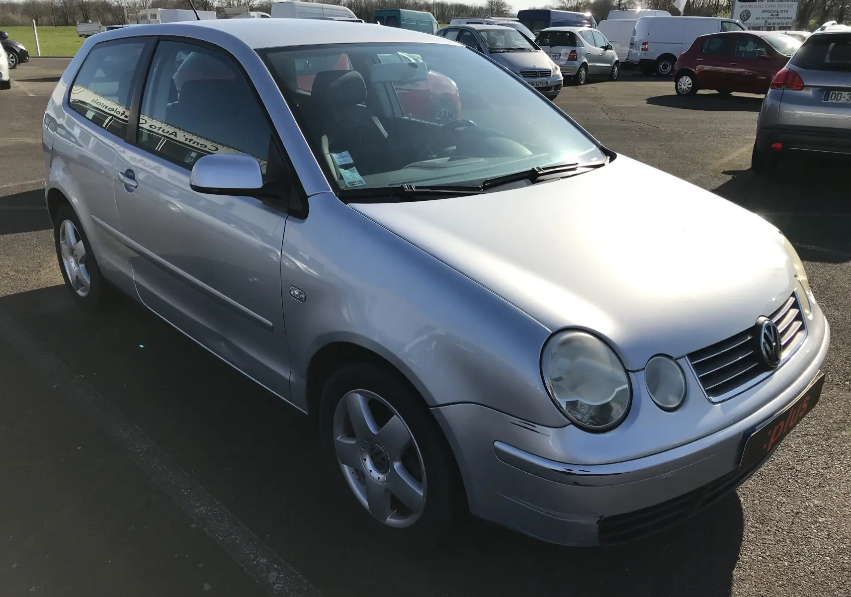 Volkswagen Polo Match gris argent vue 3/4 avant droit, avec jantes alliage et carrosserie légèrement rayée.