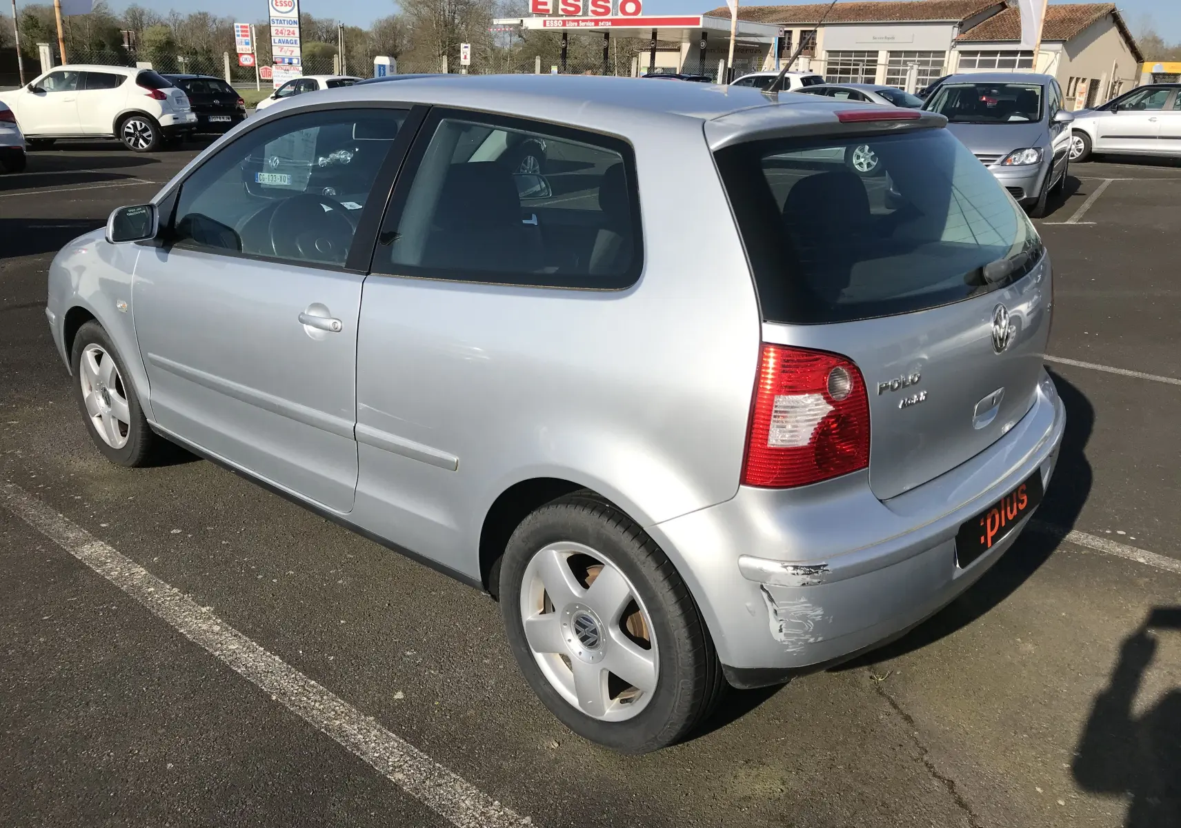 Volkswagen Polo Match gris argent vue 3/4 arrière droit avec rayure visible sur le pare-chocs.