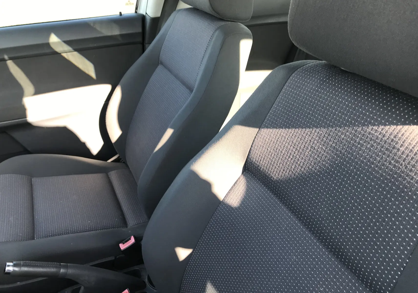 Gros plan sur les sièges avant en tissu noir de la Volkswagen Polo Match 2004, ambiance intérieure lumineuse.