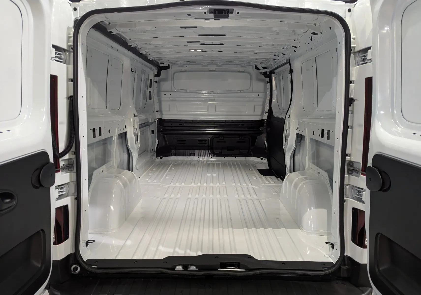 Vue arrière ouverte du Renault Trafic Fourgon blanc minéral L2H1 2025, montrant l'intérieur vide et spacieux de la zone de chargement.