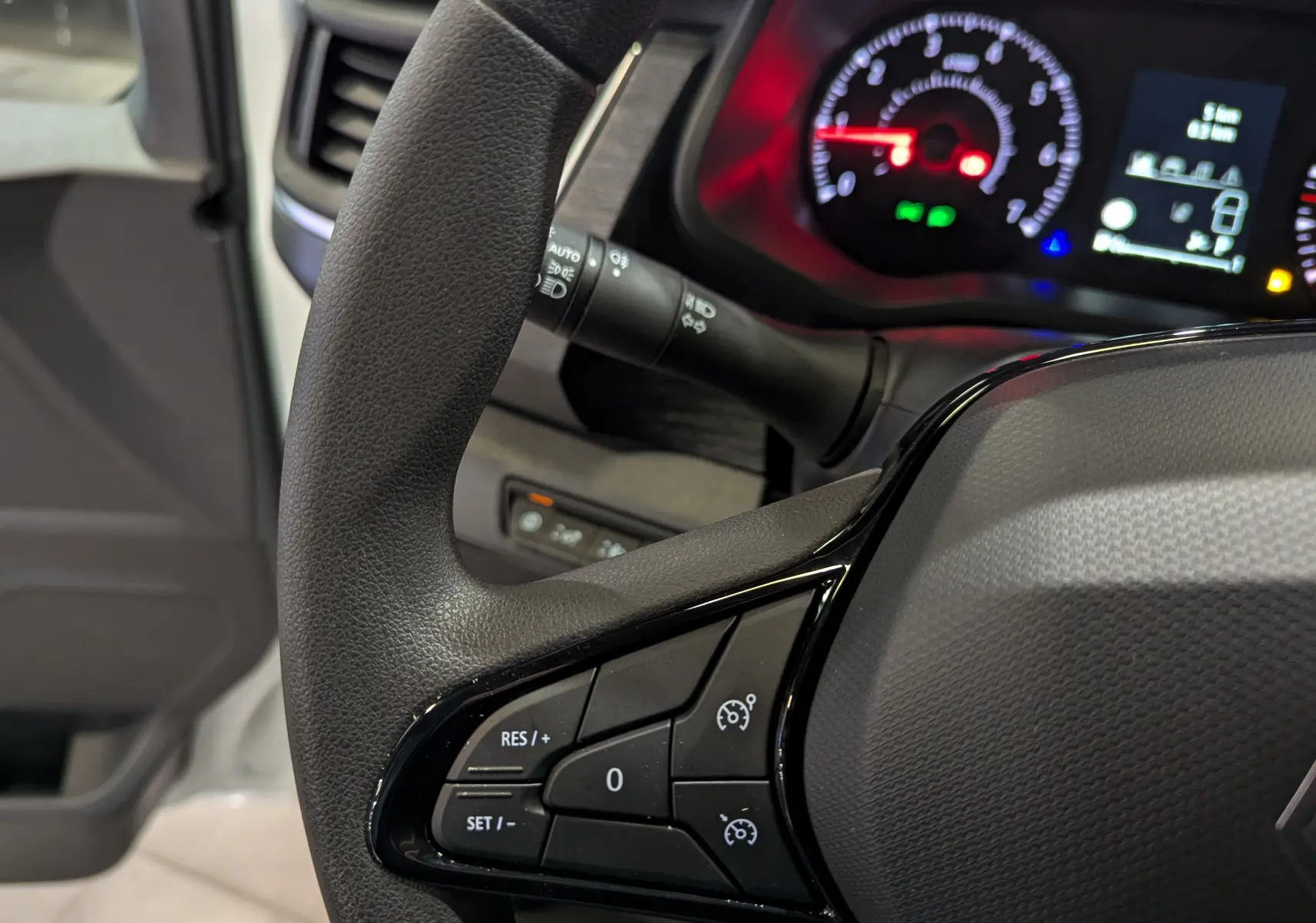 Gros plan sur le volant et le tableau de bord du Renault Trafic Fourgon blanc, avec commandes de régulateur de vitesse visibles.