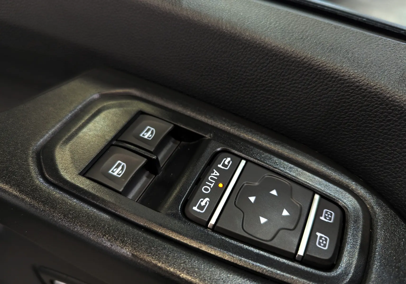 Gros plan sur les commandes de lève-vitres et réglage des rétroviseurs côté gauche du Renault Trafic Fourgon blanc 2025.