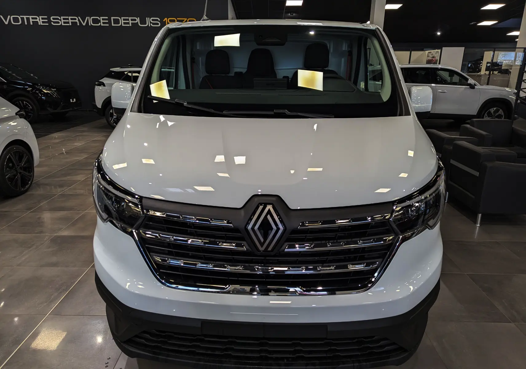 Vue frontale d'un Renault Trafic Fourgon blanc minéral 2025 avec calandre chromée et logo Renault bien visible.