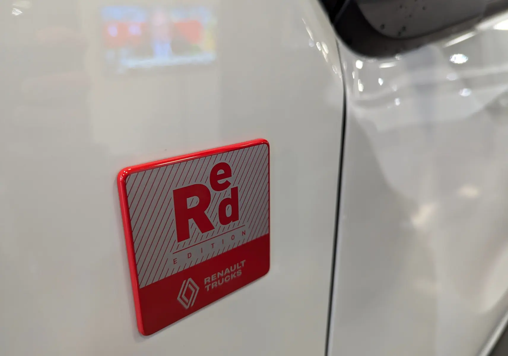 Gros plan sur l'écusson rouge "Red Edition" sur la porte blanche minéral d'un Renault Trafic Fourgon 2025.