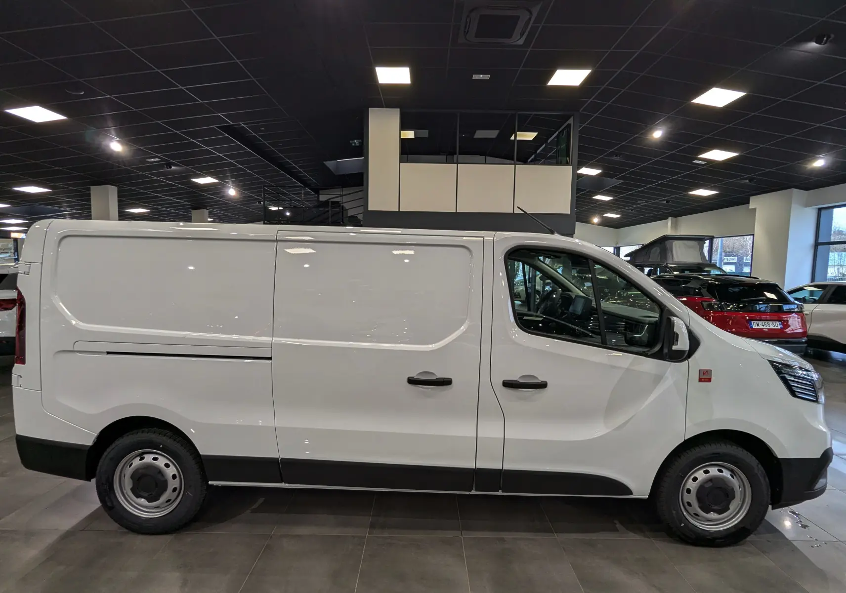 Profil droit d’un Renault Trafic Fourgon blanc minéral 2025, avec portes latérales et jantes acier en showroom.
