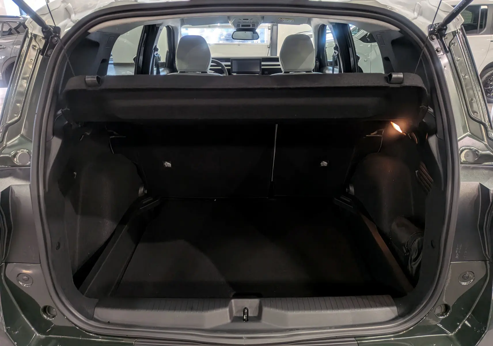 Coffre ouvert vu de l'arrière d'un Citroën C3 Aircross Vert Montana avec toit blanc, intérieur noir et sièges avant visibles.