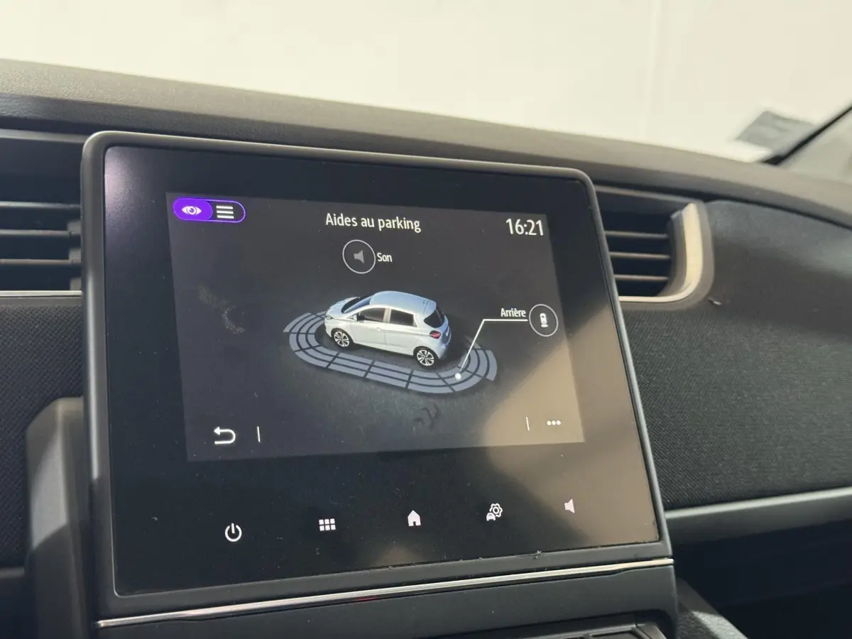 Écran tactile central montrant l'aide au stationnement de la Renault ZOE blanche, vue intérieure du tableau de bord.