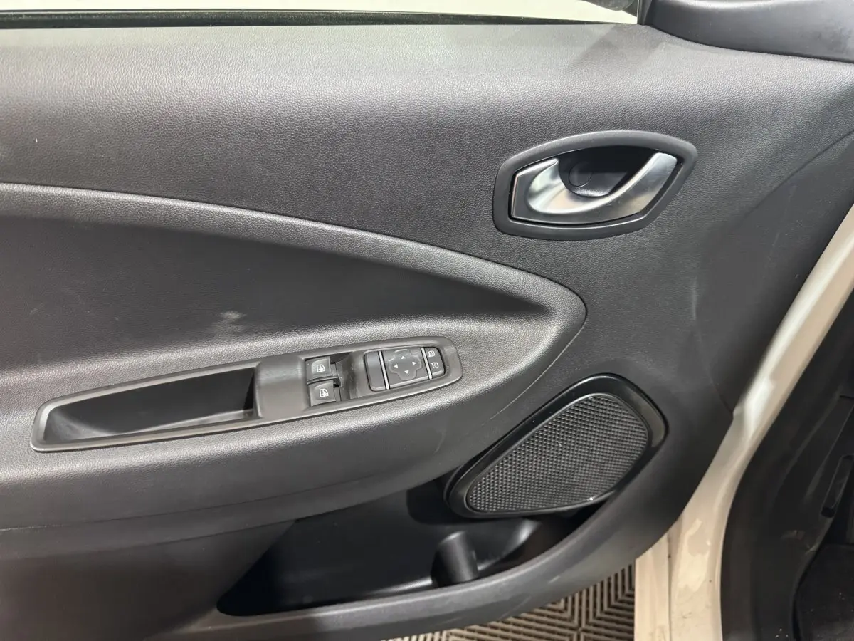 Vue intérieure côté gauche de la porte avant blanche de la Renault ZOE 2020 avec commandes électriques et haut-parleur intégré.