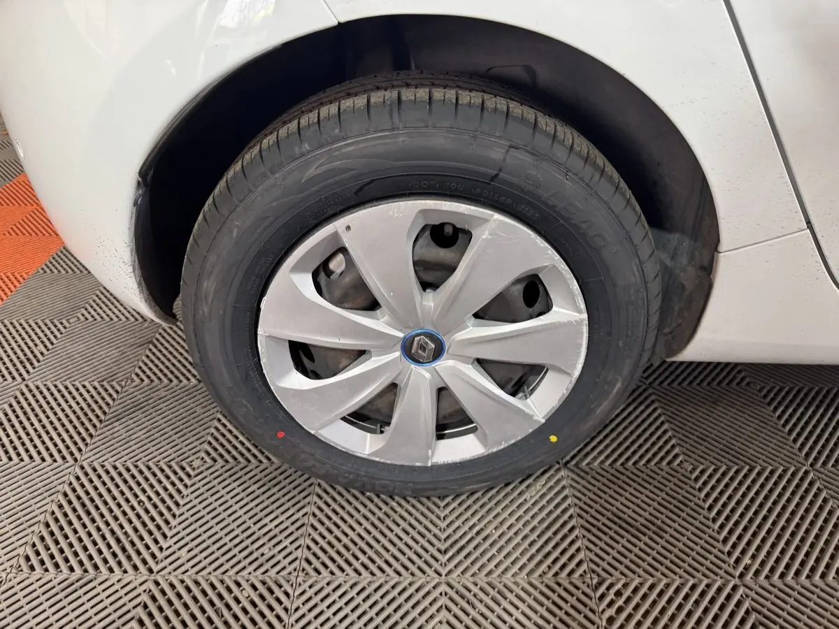 Gros plan sur la roue avant droite blanche d'une Renault ZOE 2020 avec enjoliveur gris et logo Renault central.