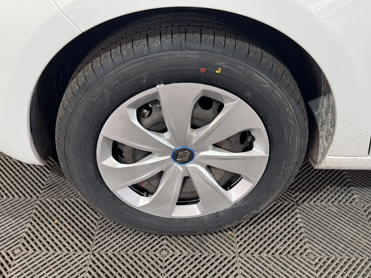 Gros plan sur la roue avant droite d'une Renault ZOE blanche avec enjoliveur argenté et logo Renault au centre.
