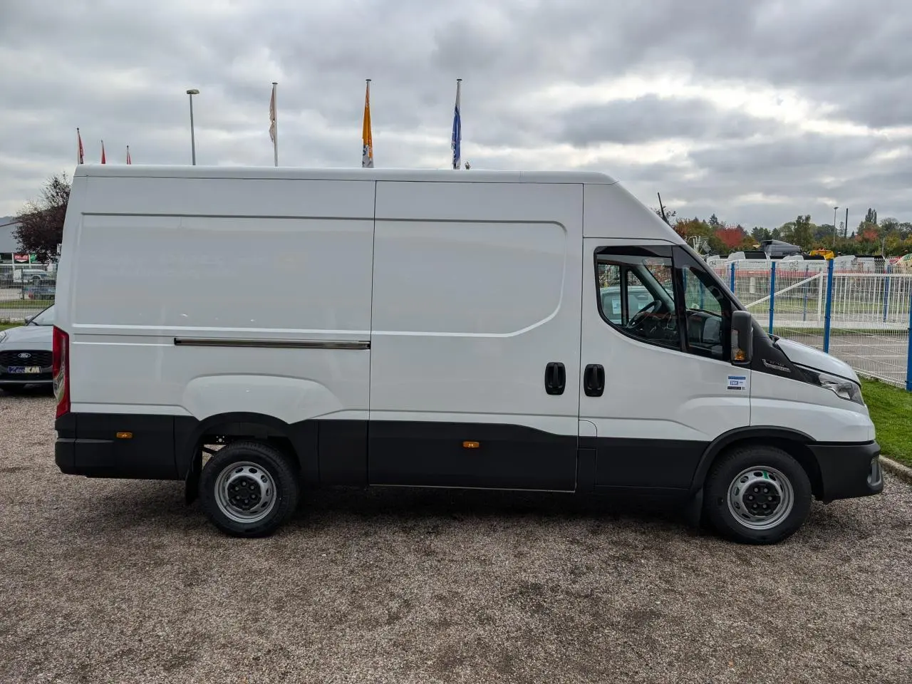 Vue de profil droit d’un utilitaire Iveco Daily blanc avec portes coulissantes et bas de caisse noir.