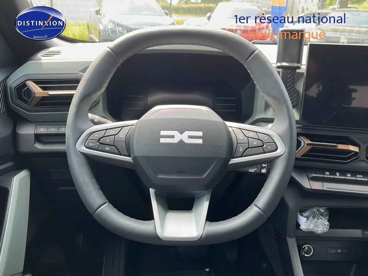 Vue centrée sur le volant multifonction du Dacia Duster 2025 avec tableau de bord et écran tactile noir.