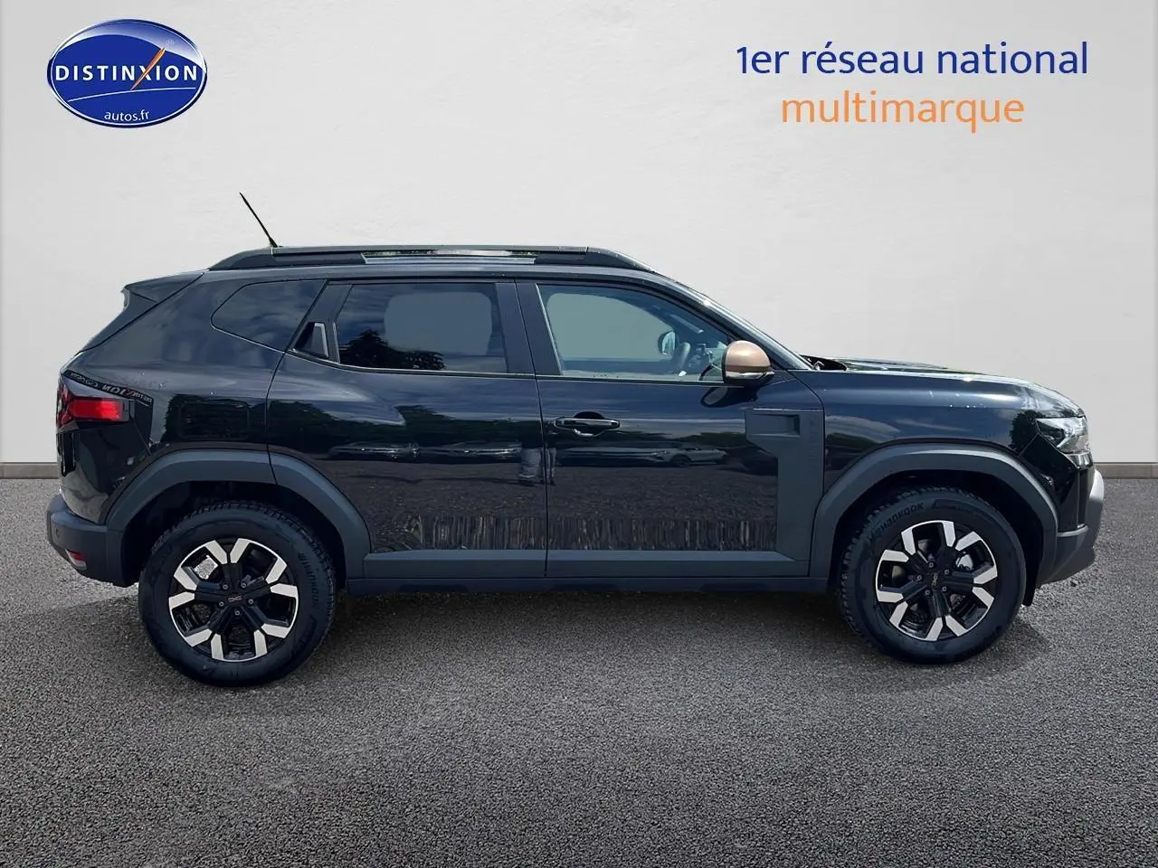 Profil côté gauche du Dacia Duster noir 2025 avec jantes alu et barres de toit visibles sur fond clair.