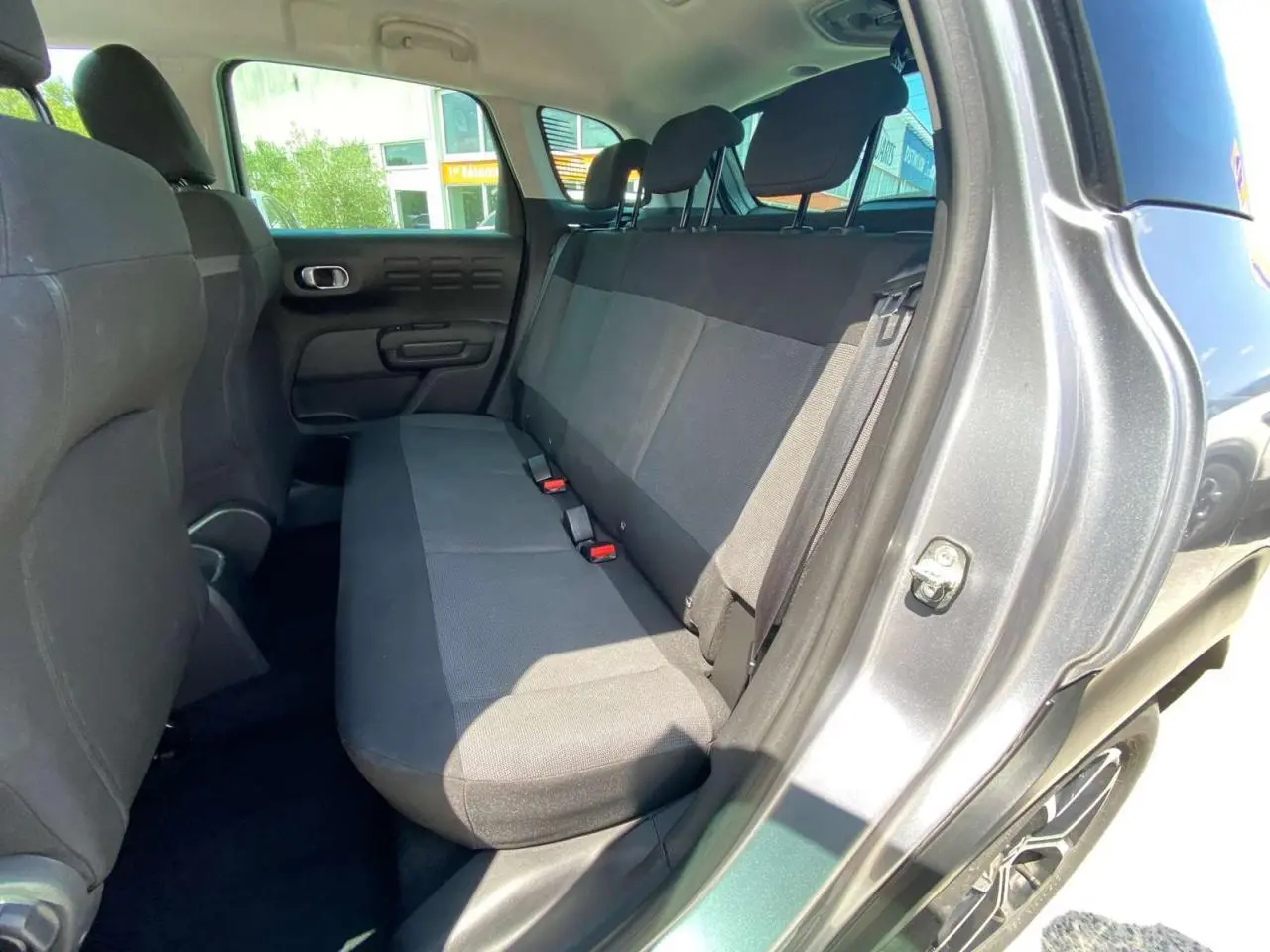 Vue intérieure côté droit sur la banquette arrière noire du Citroën C3 Aircross gris Artense avec toit blanc.