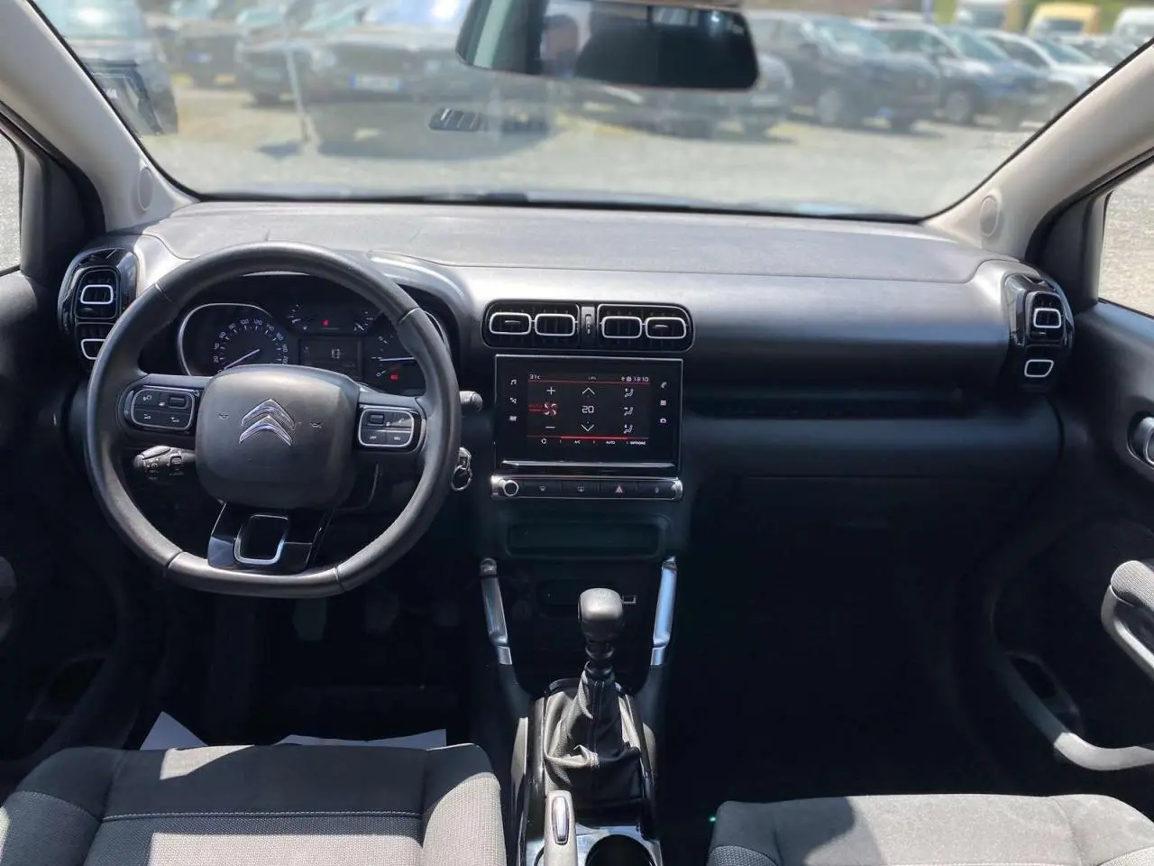 Vue intérieure avant du Citroën C3 Aircross 2023, tableau de bord noir avec volant multifonction et écran tactile central.