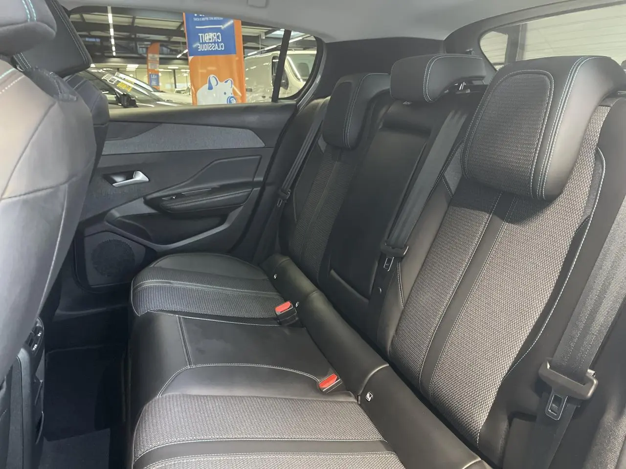 Vue intérieure côté droit des sièges arrière en sellerie tri matières noire avec surpiqûres bleues d'une Peugeot 308 2022.