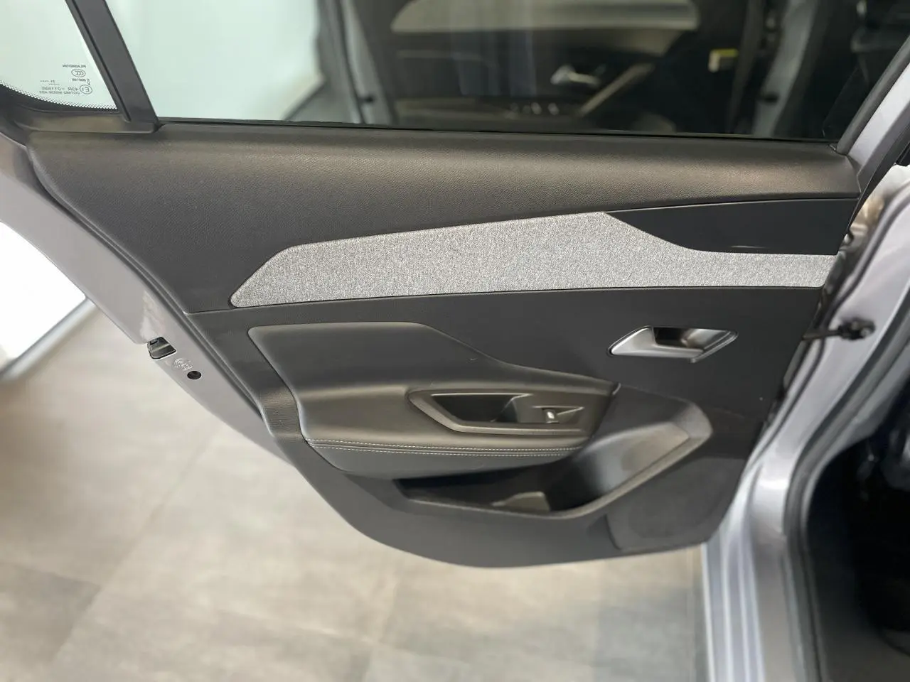 Gros plan sur la porte arrière gauche gris Artense de la Peugeot 308 2022 avec insert textile gris et poignée argentée.
